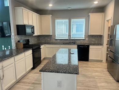 Kitchen featuring black appliances, white cabinet