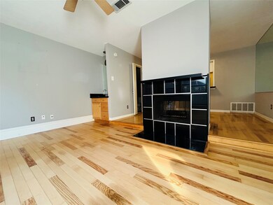 Unfurnished living room featuring a tile fireplace, light wood-style floors, and ceiling fan