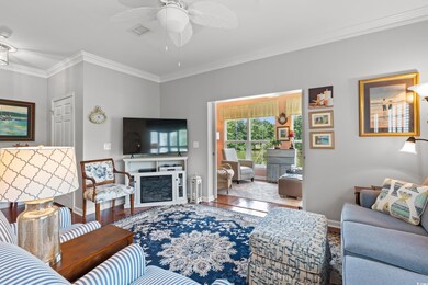 Living room featuring wood finished floors, crown molding, ceiling fan, and a fireplace