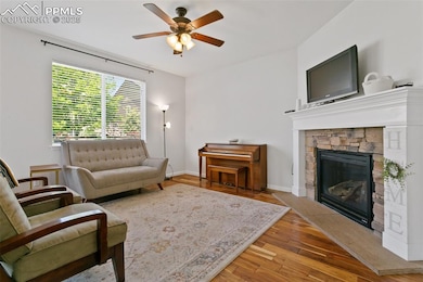 Living room featuring wood finished floors, ceiling fan, and a gas fireplace