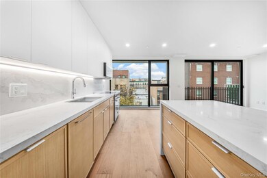 Kitchen with light stone counters, light wood-style flooring, modern cabinets, recessed lighting, and backsplash