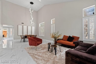 Living area with light marble finish flooring and high vaulted ceiling