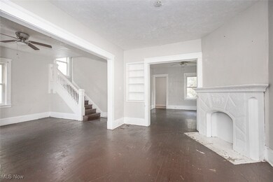Unfurnished living room featuring a ceiling fan, a textured ceiling, dark wood finished floors, stairway, and a fireplace with flush hearth