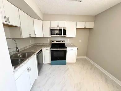Kitchen featuring white cabinetry, a textured ceil