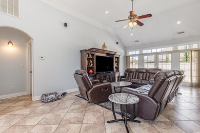 Living room featuring high vaulted ceiling, arched walkways, crown molding, recessed lighting, and ceiling fan