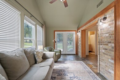 View of the living room’s window-lined wall and cozy corner seating, making the room feel airy and inviting.