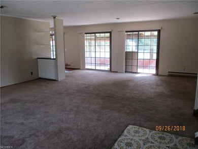 The living room includes a cabinet and glass shelv