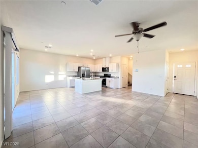 Kitchen featuring open floor plan, white cabinets, appliances with stainless steel finishes, a kitchen island with sink, and light countertops