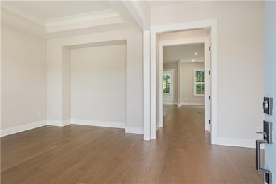 Unfurnished room featuring dark wood-style flooring, baseboards, and a raised ceiling