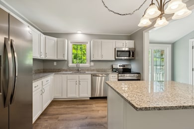Beautifully remodeled kitchen with brand new cabinets, gorgeous granite counters, stainless steel appliances, an island, and an abundance of cabinet and counter space