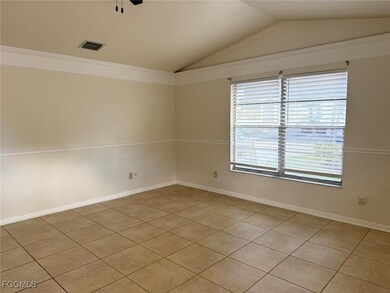 Spare room with lofted ceiling, light tile patterned floors, crown molding, and a ceiling fan