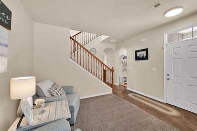 Entryway with arched walkways, stairway, and wood finished floors
