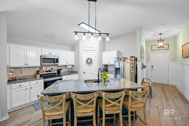 Kitchen featuring a breakfast bar, dark stone counters, white cabinetry, backsplash, and vaulted ceiling
