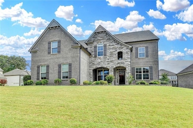 View of front facade with a front lawn, brick siding, and stone siding
