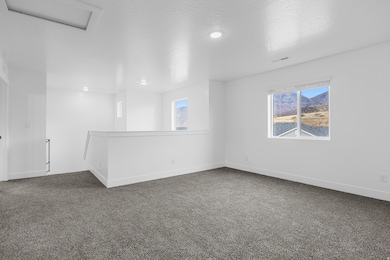 Carpeted spare room featuring a textured ceiling and baseboards