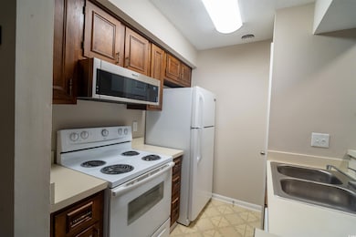 Kitchen featuring white appliances, a sink, light countertops, and baseboards