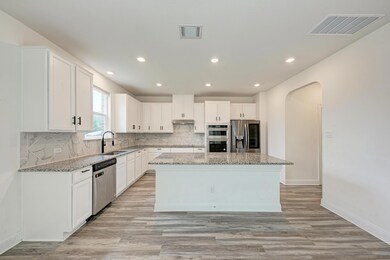 Kitchen with arched walkways, light stone counter