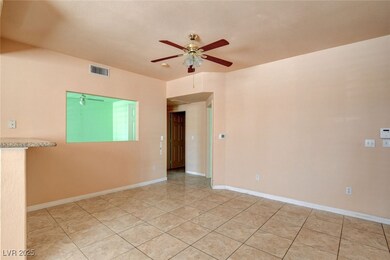 Empty room with a ceiling fan and light tile patterned flooring