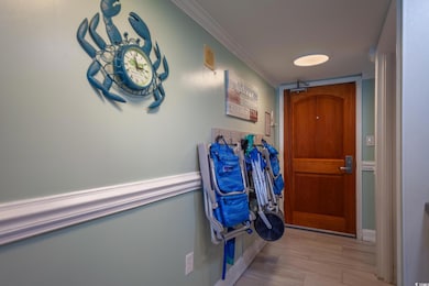 Hallway with ornamental molding and light wood-style flooring