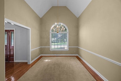 Empty room with dark wood-type flooring, a chandelier, and high vaulted ceiling