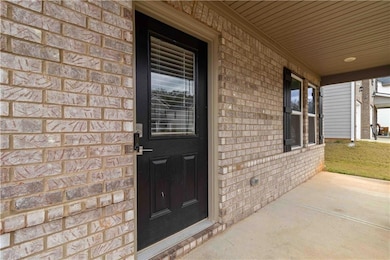 Property entrance featuring brick siding and covered porch