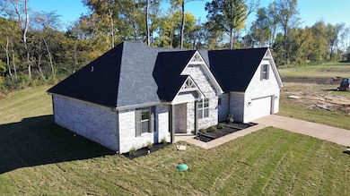 View of front facade featuring a front lawn, driveway, and brick siding
