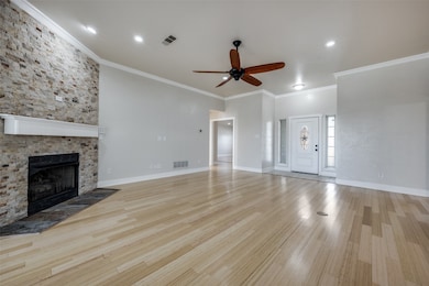 Unfurnished living room featuring ornamental molding, a fireplace, light wood-style floors, and ceiling fan