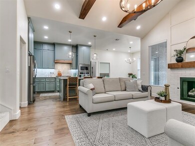 Living room featuring a notable chandelier, lofted ceiling with beams, light hardwood / wood-style flooring, and a fireplace
