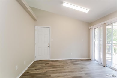 Empty room with vaulted ceiling and wood finished floors