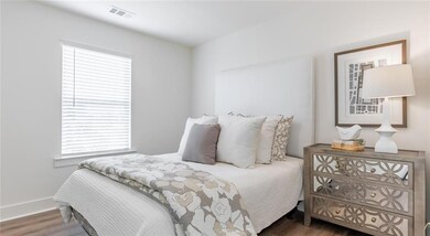 Bedroom with multiple windows, wood finished floors, and baseboards