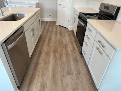 Kitchen with white cabinetry, wood-type flooring, 