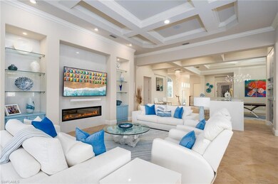 Living area featuring built in features, coffered ceiling, beam ceiling, ornamental molding, and a glass covered fireplace