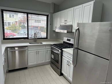 Kitchen featuring stainless steel appliances, white cabinets, under cabinet range hood, and light stone counters