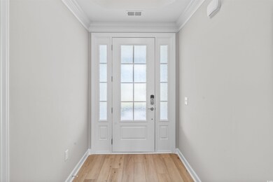Entryway featuring wood finished floors and crown molding