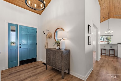 Foyer featuring wooden ceiling, a chandelier, high vaulted ceiling, and wood finished floors