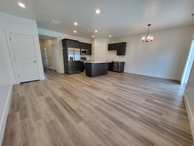Kitchen with open floor plan, stainless steel appliances, recessed lighting, light countertops, and decorative light fixtures