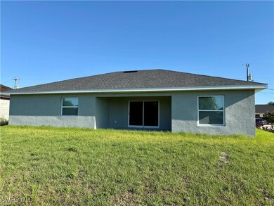 Back of property featuring stucco siding and a law
