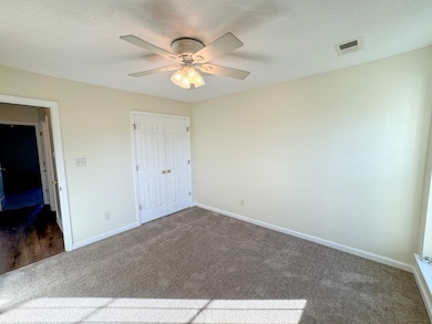 Unfurnished bedroom with dark carpet, baseboards, a closet, ceiling fan, and a textured ceiling