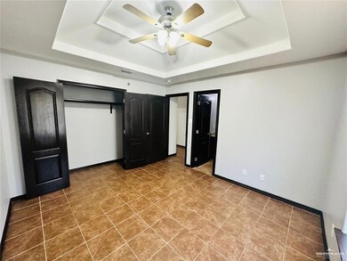 Unfurnished bedroom featuring a tray ceiling, baseboards, ceiling fan, visible vents, and tile patterned floors