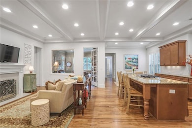 Kitchen featuring light wood-type flooring, a kitchen island, stainless steel gas stovetop, beam ceiling, and a breakfast bar area