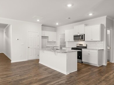 Robie open concept kitchen with hardwood like flooring and stainless steel appliances