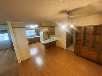 Kitchen featuring a peninsula, light countertops, brown cabinets, light wood-style flooring, and a textured ceiling