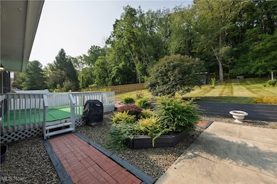 Fenced backyard with a deck, a grill, and view of wooded area