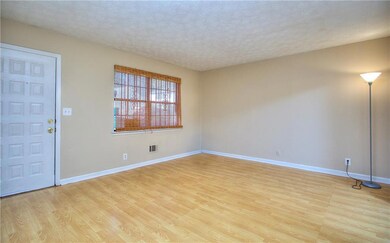 Empty room featuring baseboards, light wood-type flooring, and a textured ceiling