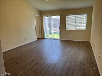 Empty room with dark wood-style flooring, baseboar