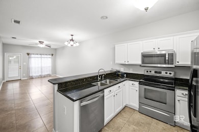 Kitchen with stainless steel appliances, white cabinetry, light tile patterned flooring, and a textured ceiling