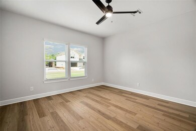 Spacious primary suite with natural light and modern ceiling fan.
