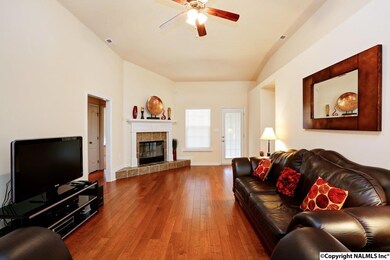 The family rooms offers wood floors, a vaulted ceiling, a ceiling fan, and a wood-burning fireplace with raised hearth.