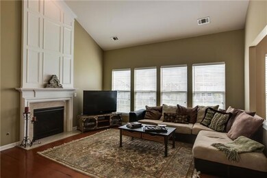 The great room is open and inviting featuring a vaulted ceiling, fireplace, and hardwood floors