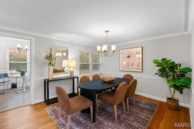 Dining space featuring a chandelier, wood finished floors, and crown molding